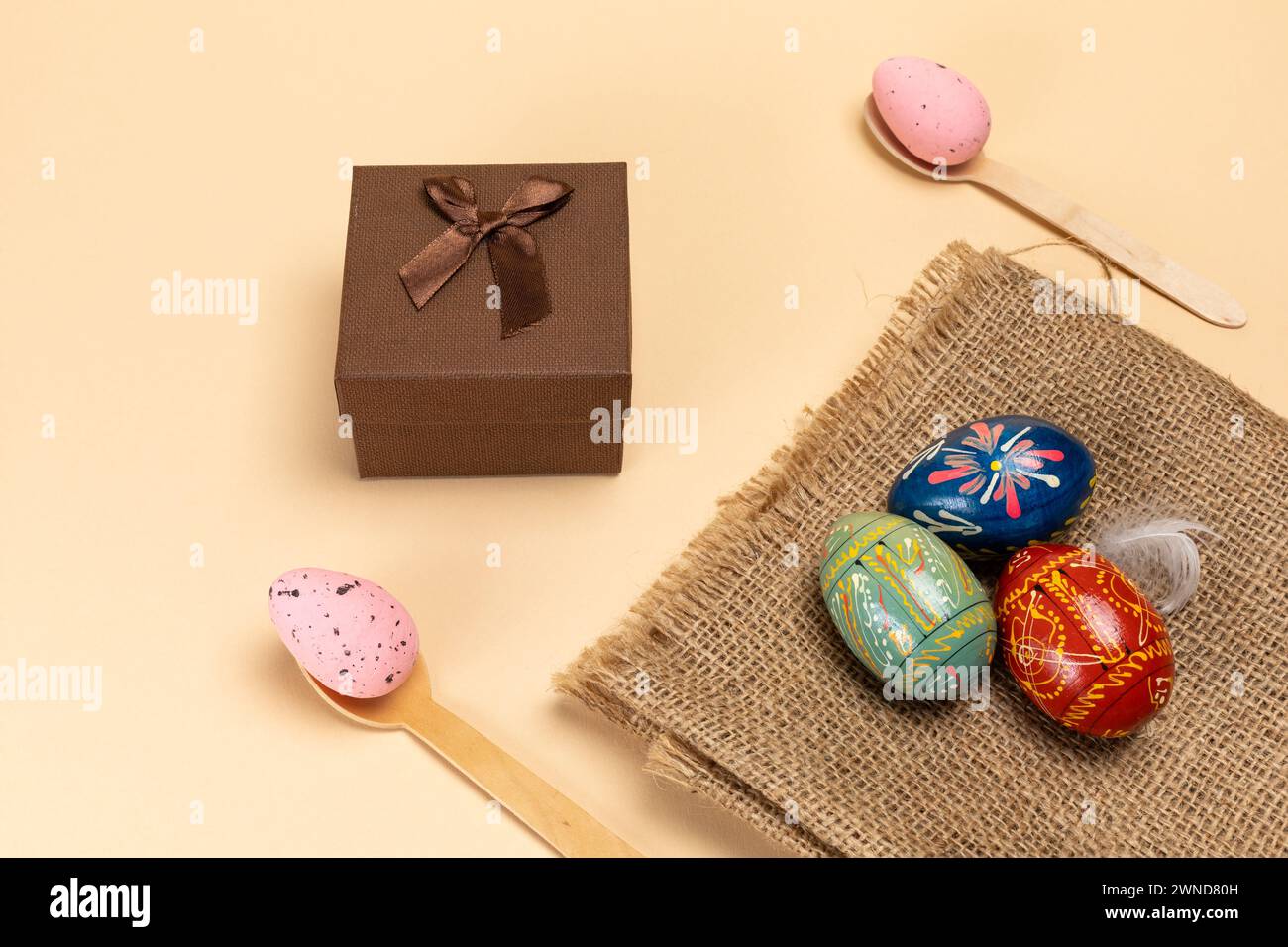 Oeufs de Pâques colorés sur un sac de sac et cuillères en bois avec une boîte cadeau. Vue de dessus. Banque D'Images