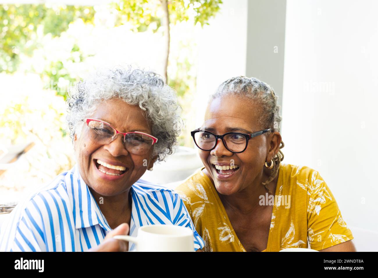 Senior afro-américaine et femme biraciale partagent un moment joyeux, riant ensemble à la maison Banque D'Images