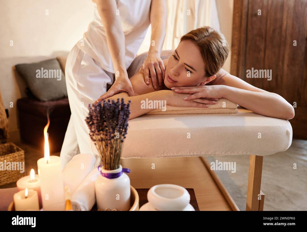 Portrait de femme mignonne pendant que les épaules et le dos massent avec les mains masseuses au spa de bien-être Banque D'Images