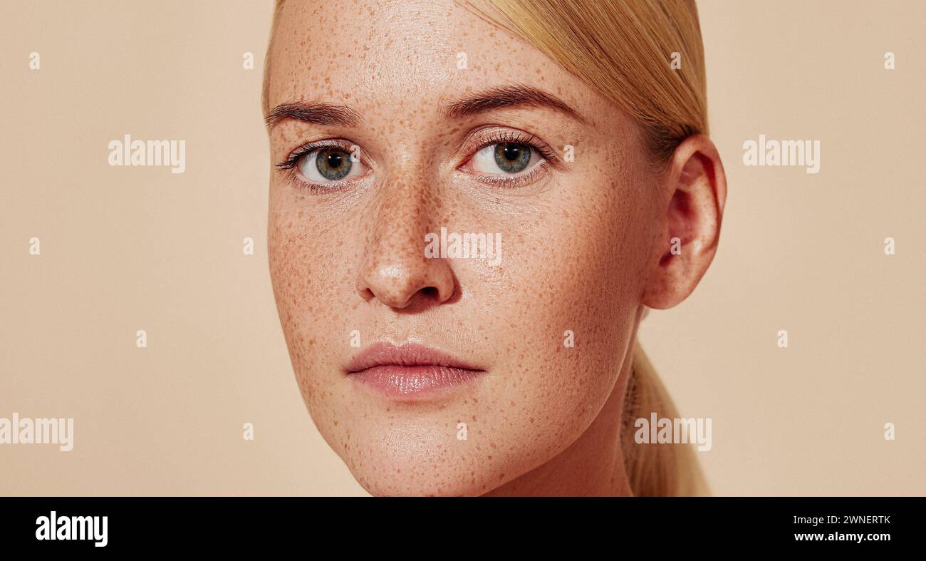 Portrait recadré d'une jeune belle femme avec des taches de rousseur. Gros plan d'une femelle avec une peau lisse. Banque D'Images