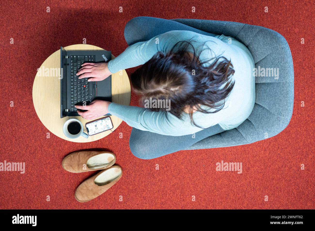 Dresde, Allemagne. 02 mars 2024. Une femme est assise dans un fauteuil dans son bureau à domicile et travaille sur un ordinateur portable (scène mise en scène). Crédit : Sebastian Kahnert/dpa/Alamy Live News Banque D'Images