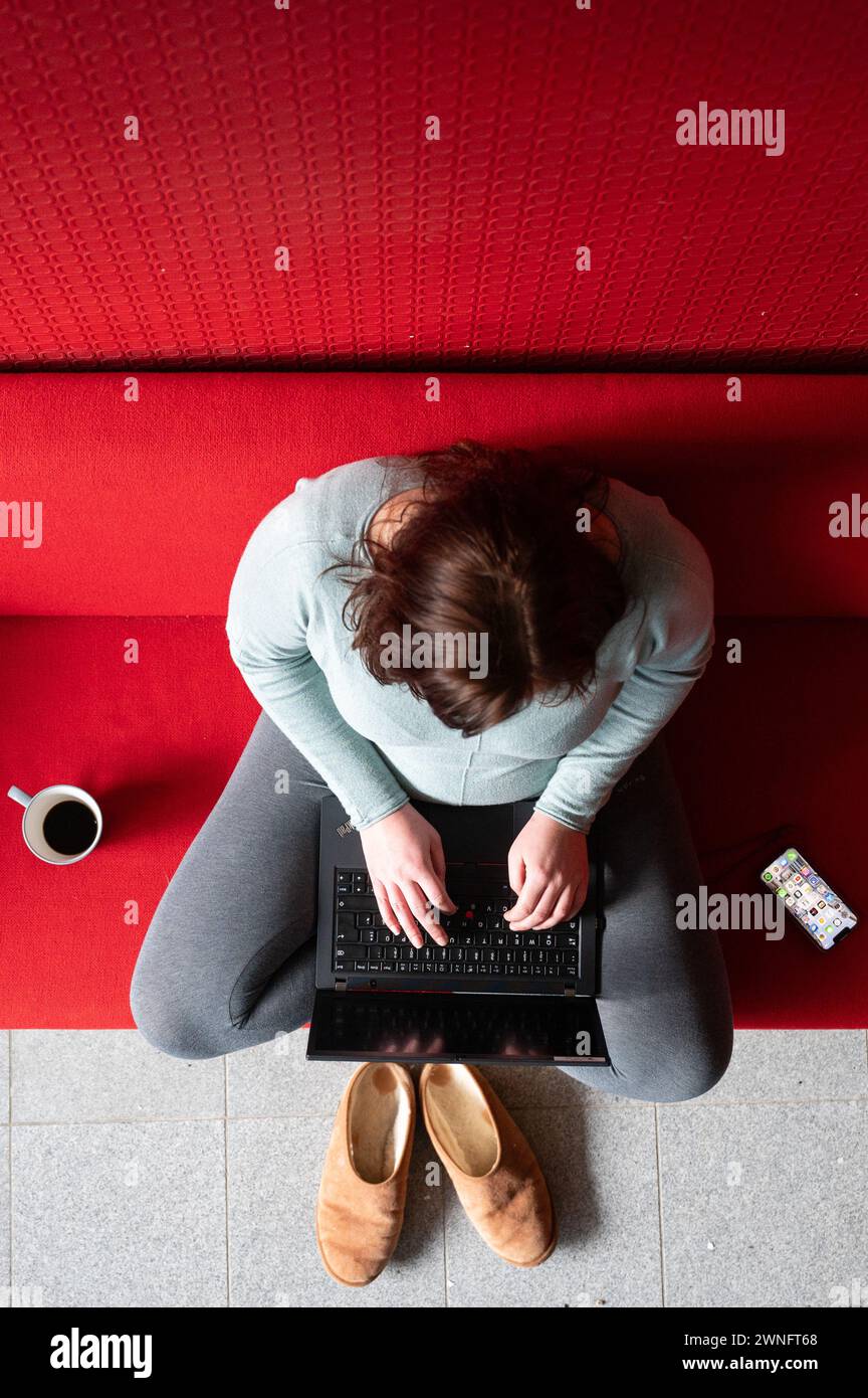 Dresde, Allemagne. 02 mars 2024. Une femme est assise sur un canapé dans son bureau à domicile et travaille sur un ordinateur portable (scène mise en scène). Crédit : Sebastian Kahnert/dpa/Alamy Live News Banque D'Images