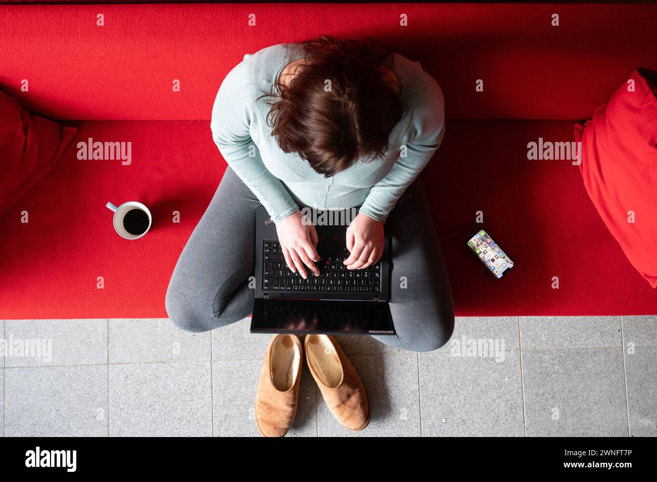 Dresde, Allemagne. 02 mars 2024. Une femme est assise sur un canapé dans son bureau à domicile et travaille sur un ordinateur portable (scène mise en scène). Crédit : Sebastian Kahnert/dpa/Alamy Live News Banque D'Images
