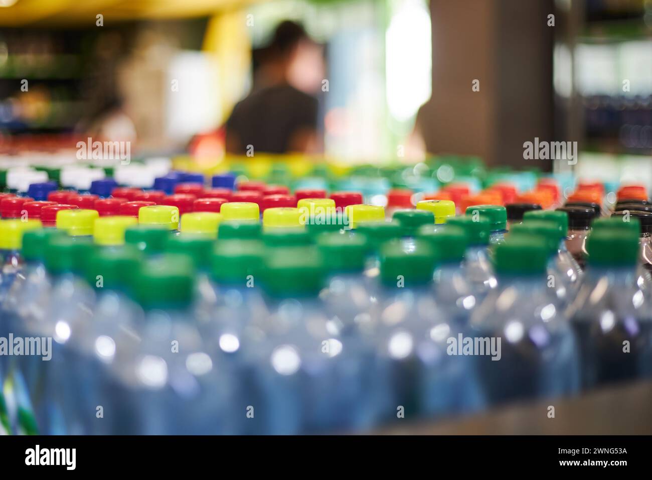 Lot de bouteilles d'eau minérale de petit volume en plastique bleu d'un demi-litre, bouchon rouge jaune vert en magasin. Plastique haute consommation dans la vie quotidienne, quel sondage Banque D'Images