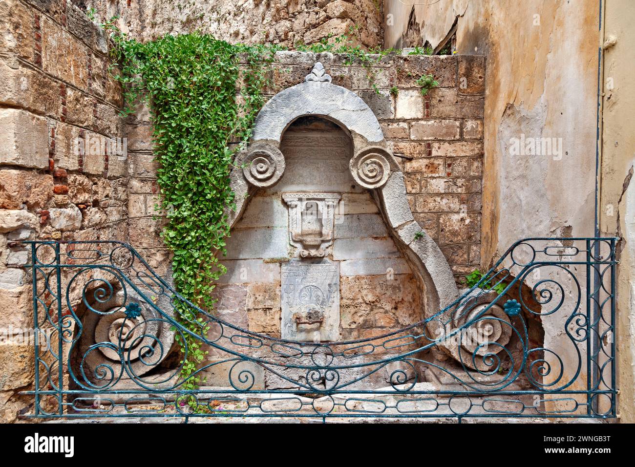 Ancienne fontaine ottomane de la fin du XVIIIe siècle, avec des écrits religieux en alphabet ottoman et protégée par une balustrade métallique, dans la vieille ville de Nauplie. Banque D'Images