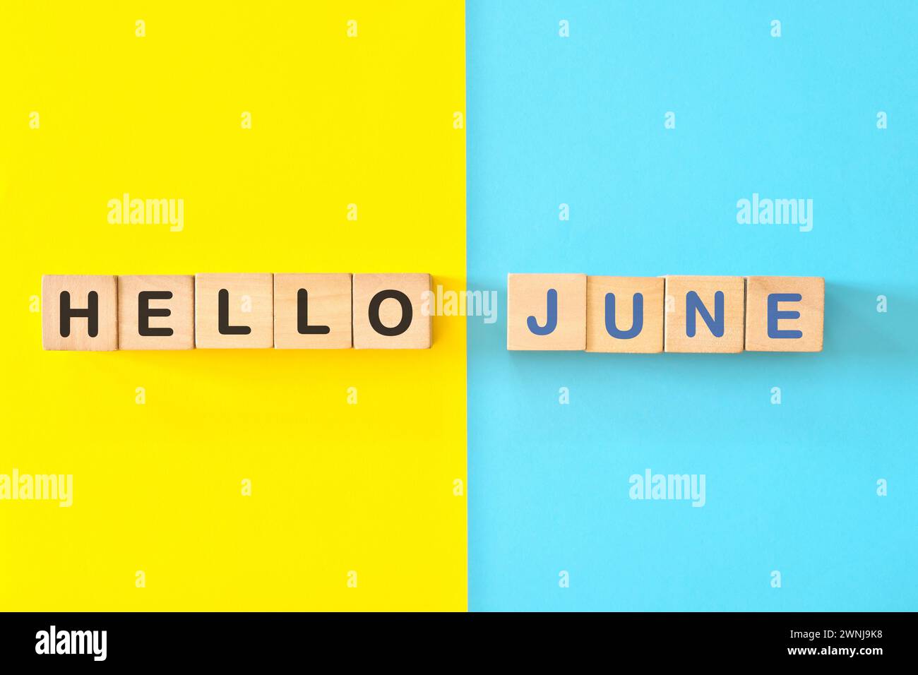 Bonjour le concept du mois de juin. Typographie de blocs en bois en fond bleu vif et jaune. Banque D'Images