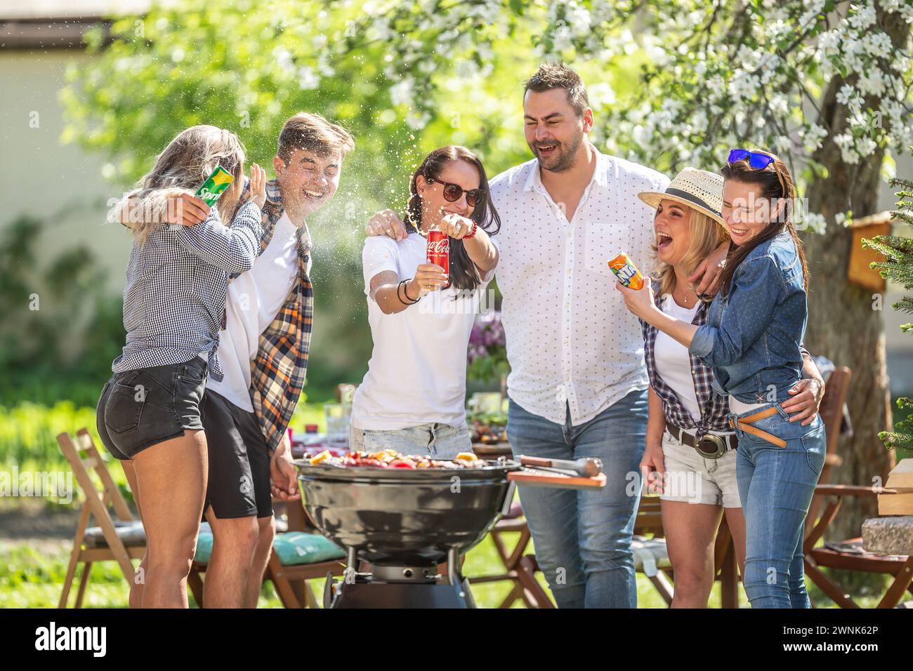 Mars. 02. 2024 Liptovsky Mikulas. Slovaquie - le groupe d'amis s'amuse pendant la fête de barbecue d'été comme une femme ouvre une bombe de pulvérisation Banque D'Images