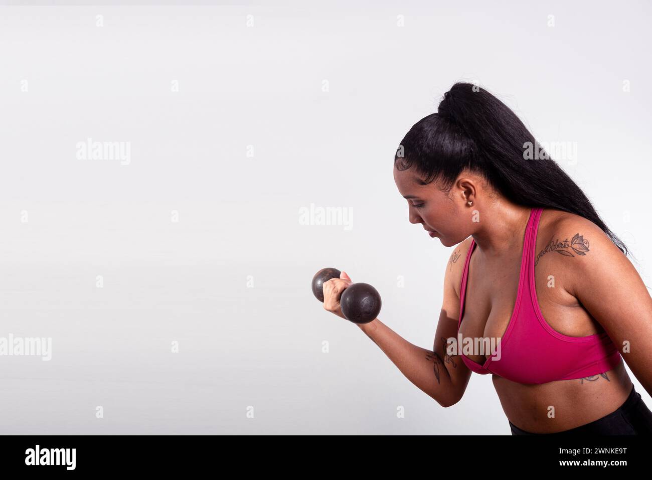 Jeune femme athlète de fitness, vêtue de vêtements de gym, faisant des exercices de bras avec des haltères. Une vie saine avec l'exercice physique. Banque D'Images