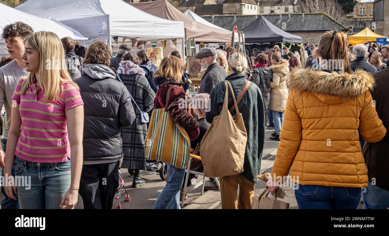 Des foules passant une dame assise au Frome Independent Sunday Market, Somerset, Royaume-Uni, le 3 mars 2024 Banque D'Images