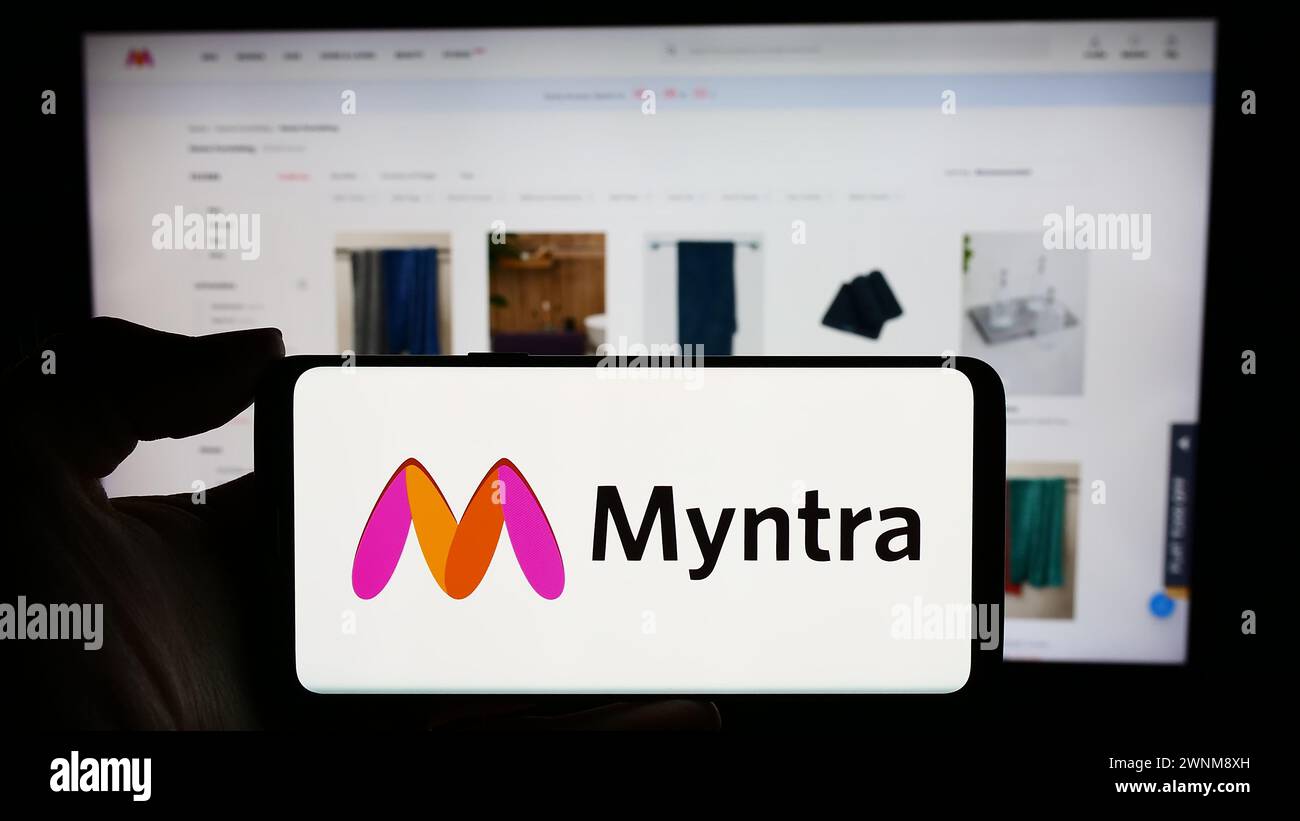 Personne tenant le téléphone portable avec le logo de la société indienne de commerce électronique Myntra Designs Pvt. Ltd devant la page Web de l'entreprise. Concentrez-vous sur l'affichage du téléphone. Banque D'Images Personne tenant le téléphone portable avec le logo de la société indienne de commerce électronique Myntra Designs Pvt. Ltd devant la page Web de l'entreprise. Concentrez-vous sur l'affichage du téléphone. Banque D'Images