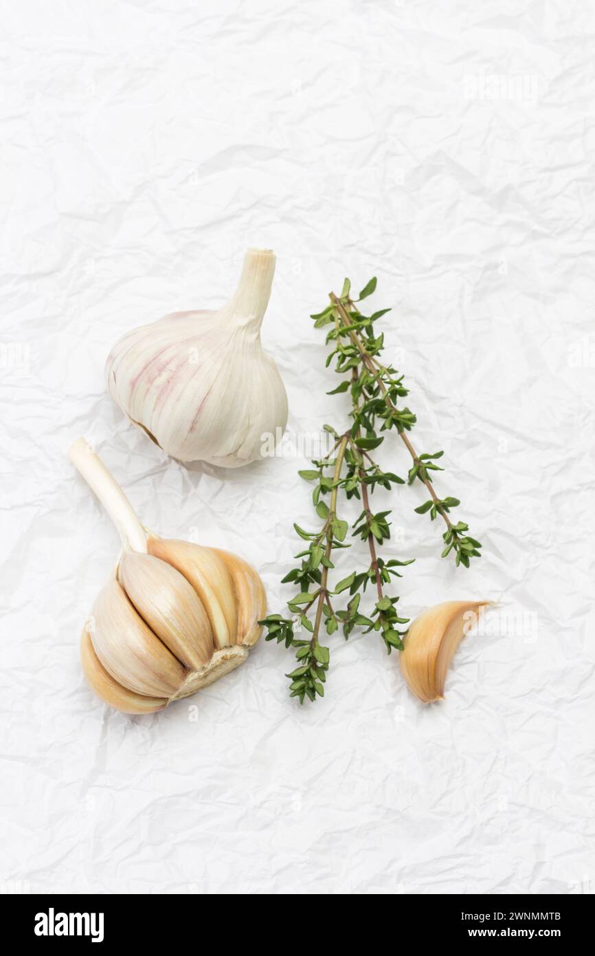 Têtes et gousses d'ail non pelées. Branches de thym. Fond blanc. Pose à plat Banque D'Images