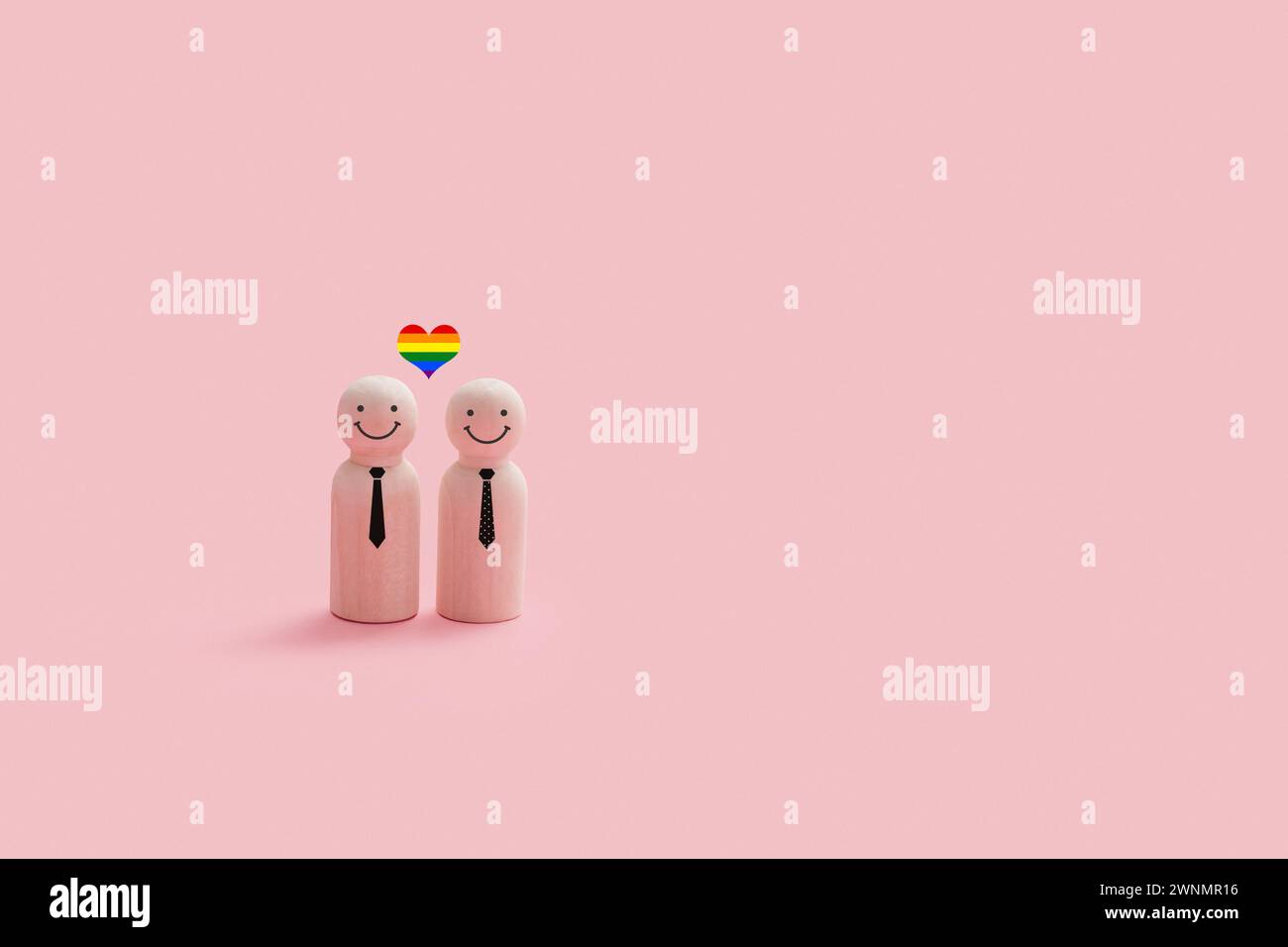 Personnages joyeux de couple gay en bois isolés sur un fond rose. Chaque figurine a un visage souriant simple, et un petit coeur de fierté couleur arc-en-ciel au-dessus de th Banque D'Images