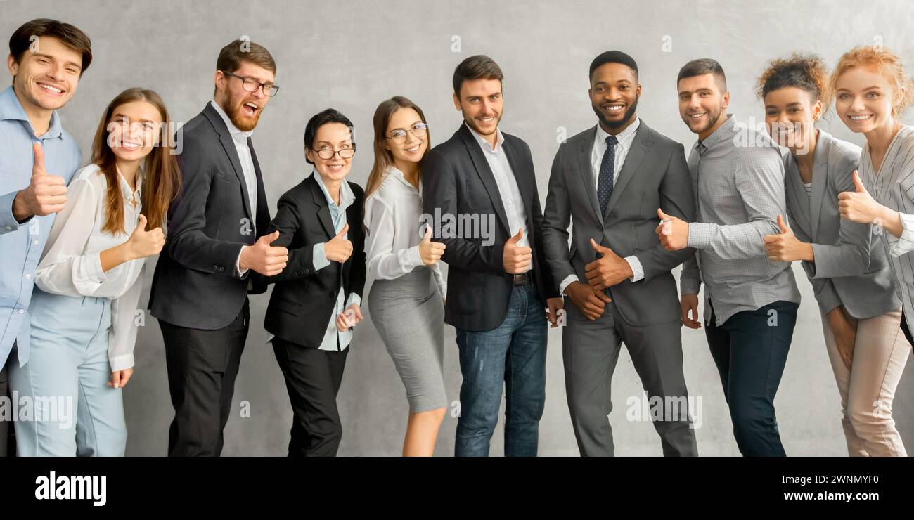 Jeune équipe d'affaires joyeuse montrant les pouces vers le haut Banque D'Images
