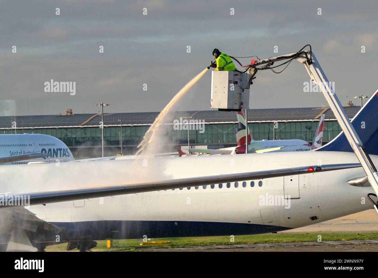 Londres, Angleterre, Royaume-Uni - 11 janvier 2024 : un employé de l'aéroport pulvérise du liquide de dégivrage sur un avion par un matin d'hiver glacial Banque D'Images