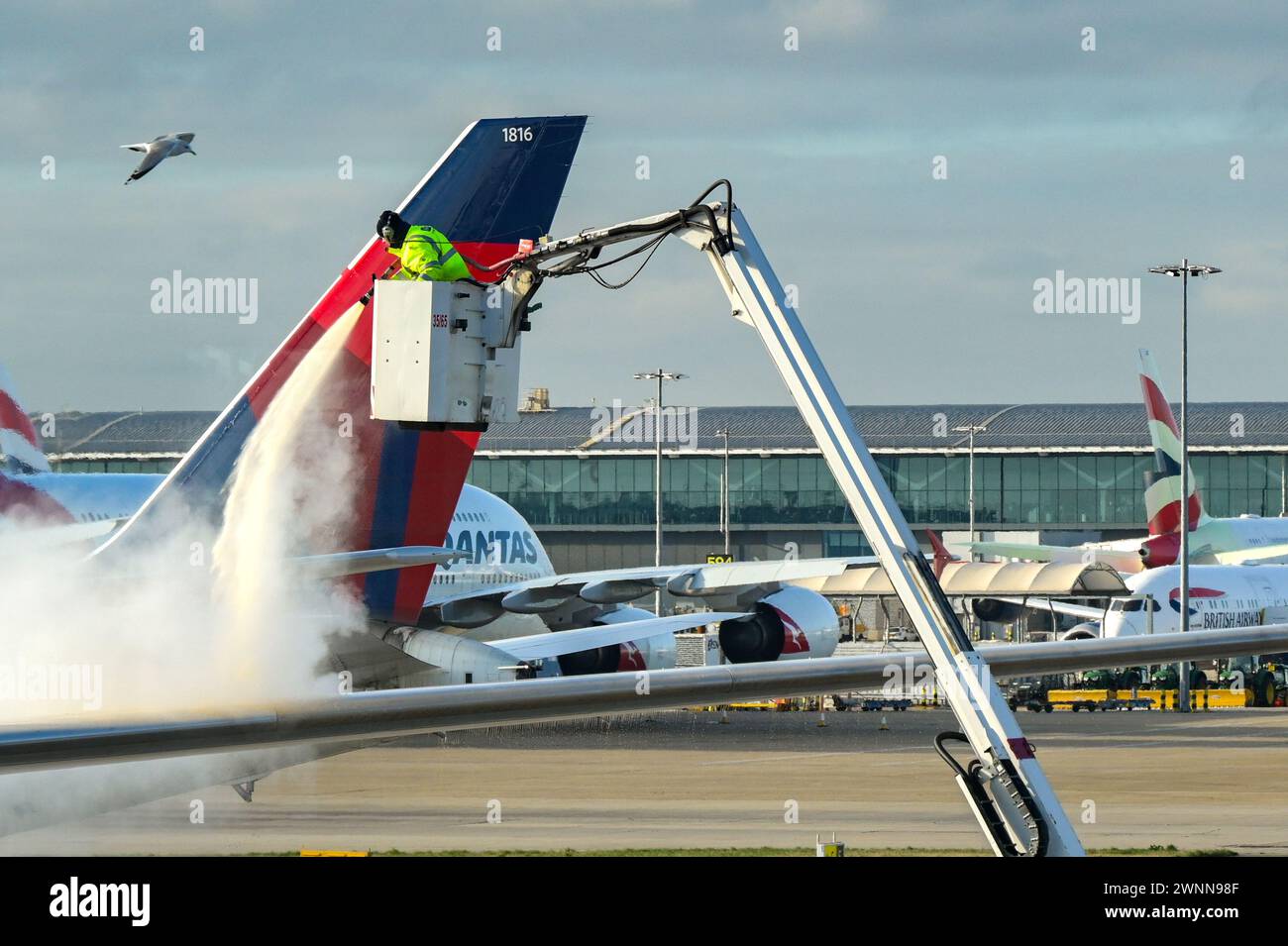 Londres, Angleterre, Royaume-Uni - 11 janvier 2024 : un employé de l'aéroport pulvérise du liquide de dégivrage sur un avion par un matin d'hiver glacial Banque D'Images