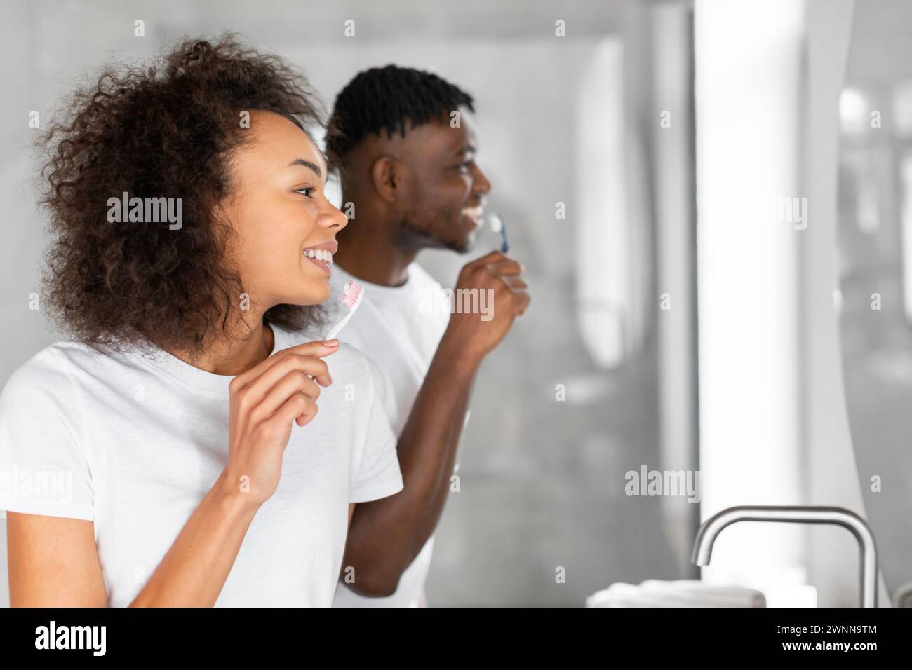 Portrait vue de côté de jeune couple noir se brossant les dents à l'intérieur Banque D'Images