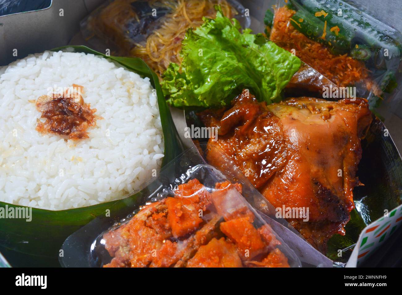 Concept alimentaire traditionnel d'Asie du Sud-est, riz enveloppé dans des feuilles de banane, poulet cuit dans de la sauce soja, salade de légumes et fruits, sur fond blanc Banque D'Images
