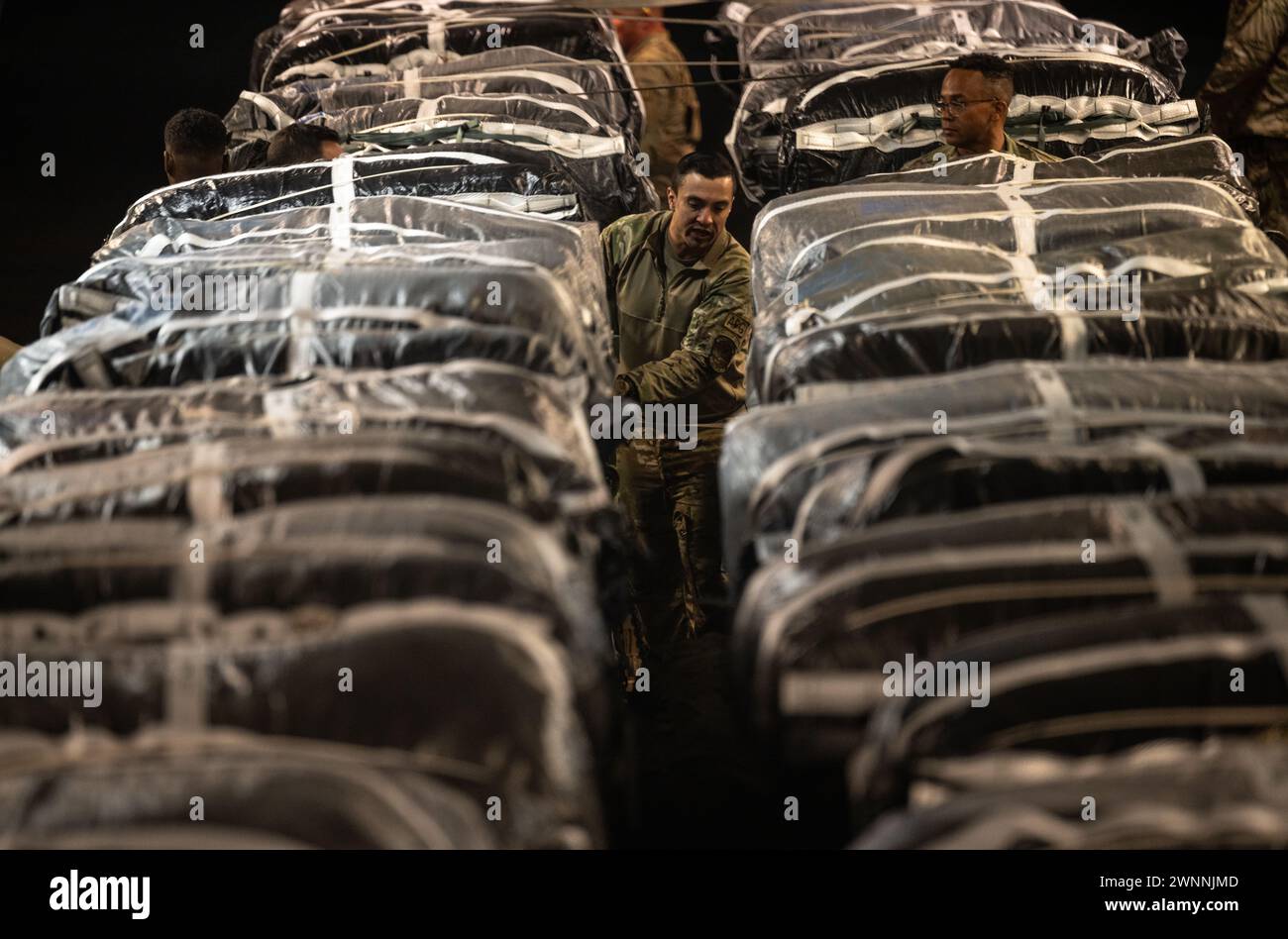 Azraq, Jordanie. 01 mars 2024. Un soldat de l'armée américaine sécurise des sangles sur des palettes d'aide humanitaire dans la soute d'un avion C-130J Super Hercules de l'US Air Force à la base aérienne Muwaffaq Salti, le 1er mars 2024 à Azraq, gouvernorat de Zarqa, Jordanie. L’aide alimentaire sera larguée par voie aérienne aux réfugiés palestiniens pris au piège de la guerre israélienne contre le Hamas. Crédit : TSGT. Christopher Hubenthal/US Airforce photo/Alamy Live News Banque D'Images