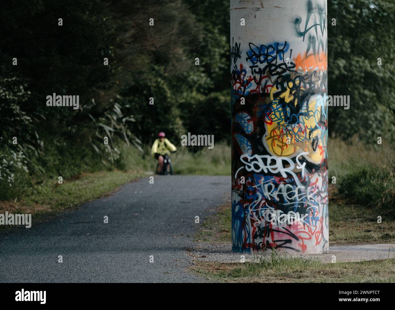 Un grand pilier en béton à côté d'une piste cyclable avec marquage et grafitti Banque D'Images