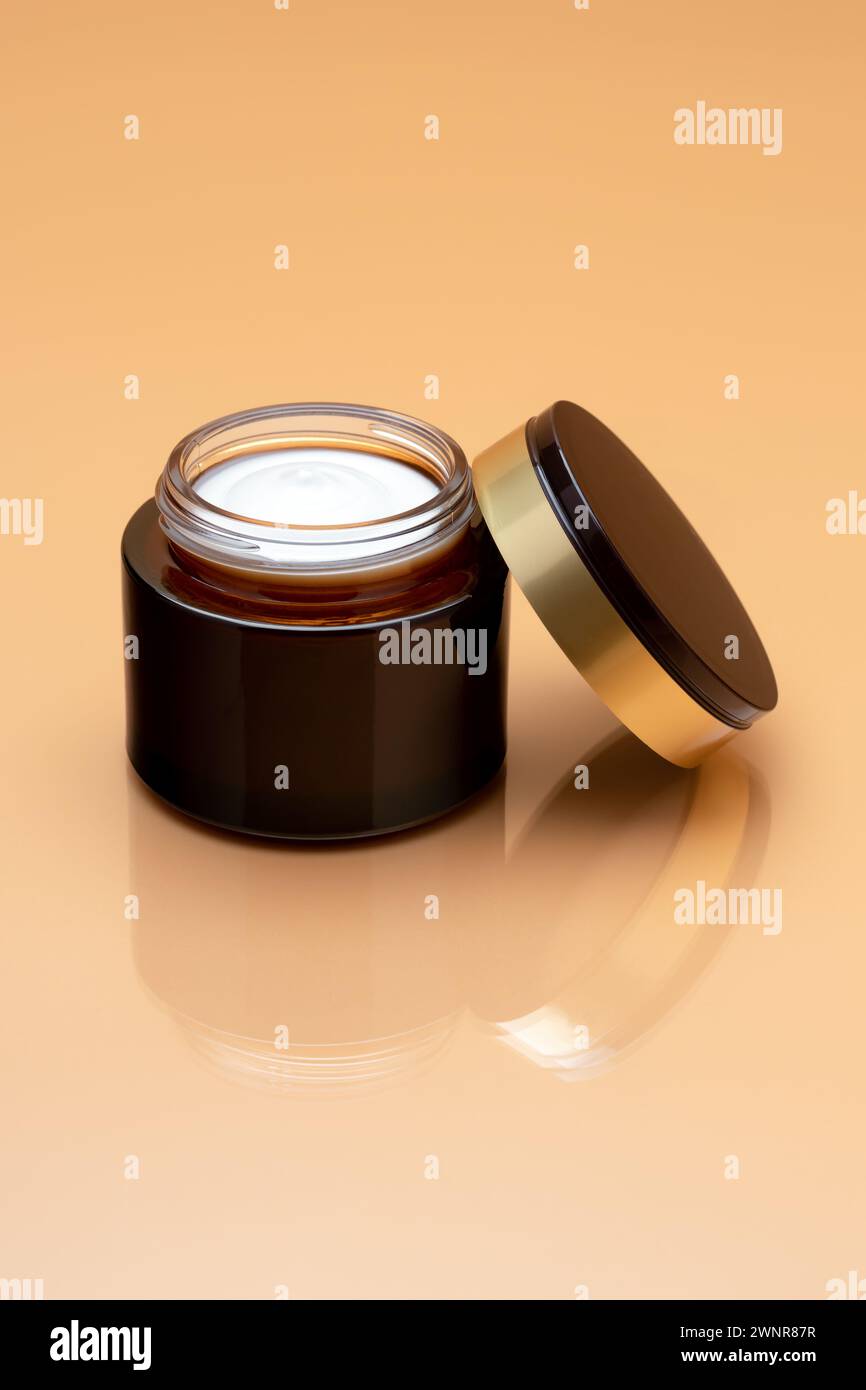 Pot de crème de visage sur fond beige. Baume anti-âge. Produit de beauté de luxe. Ouvrir le récipient avec le bouchon. Hydratant cosmétique. Espace vide pour le texte, vide Banque D'Images