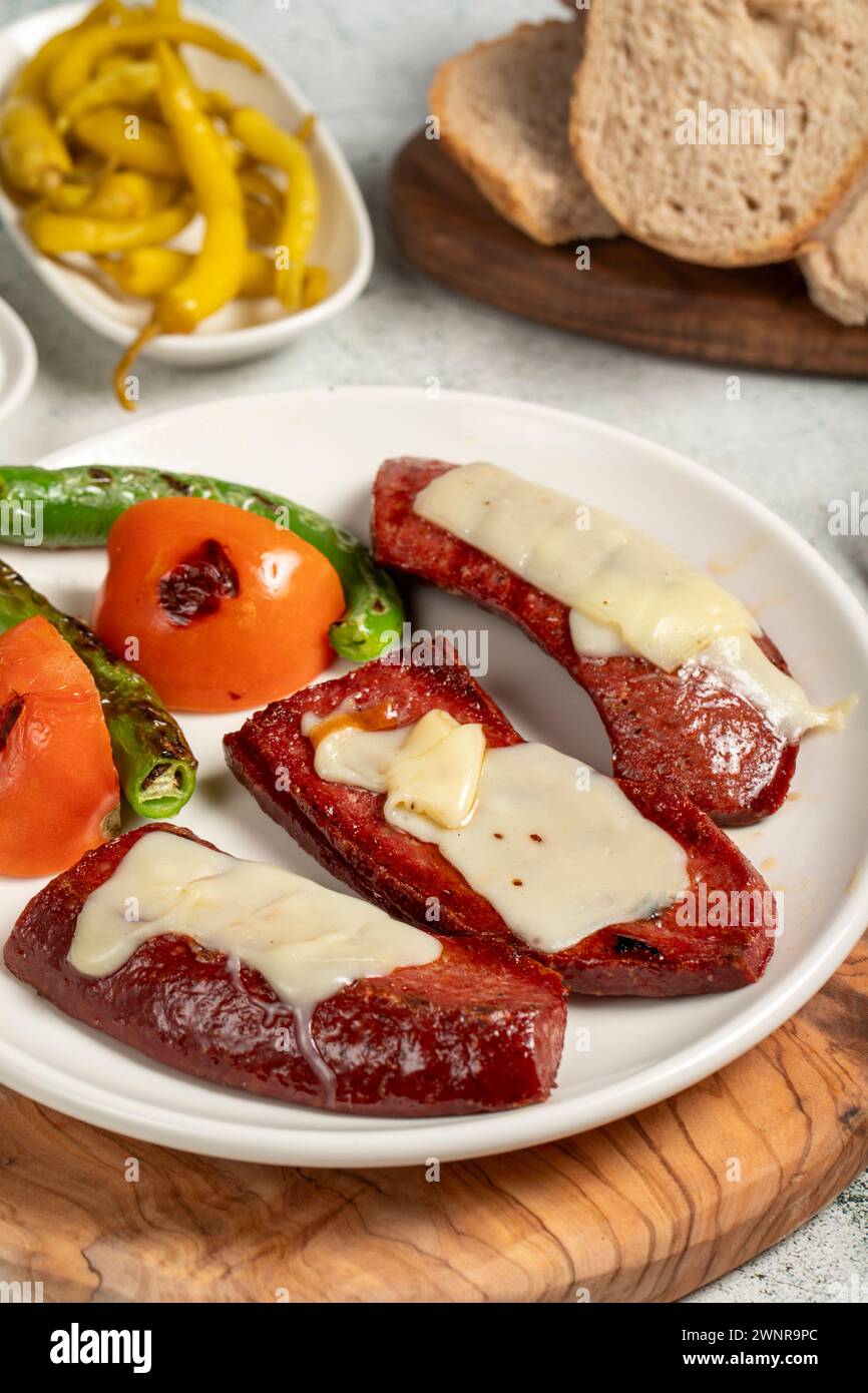 Saucisse grillée. Avec tomates, poivrons, hors-d'œuvre et sauce spéciale. Saucisse grillée avec kashar fondu sur le dessus. Gros plan Banque D'Images