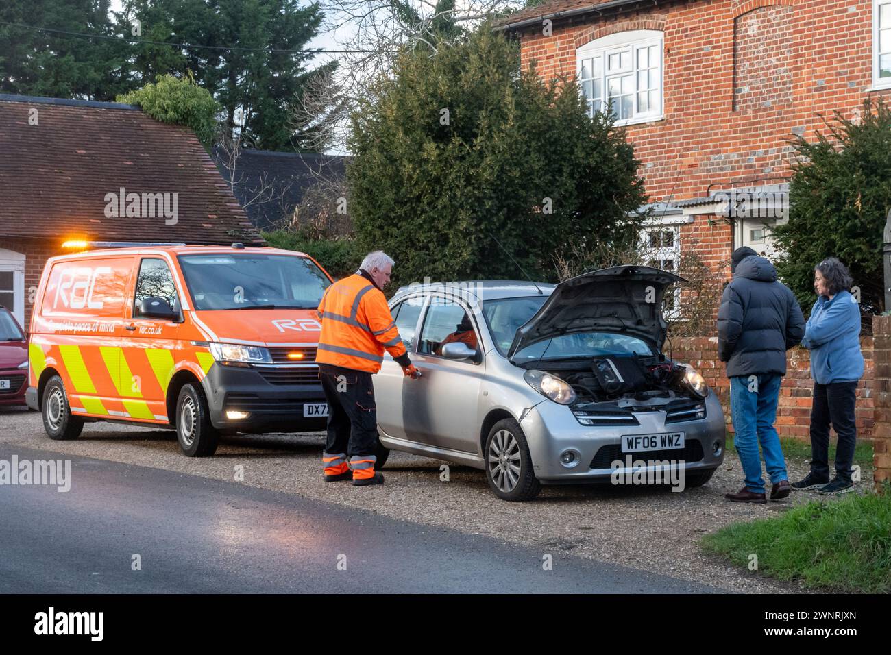 RAC dépanneur réparant une voiture en panne avec le couple ou les propriétaires debout regardant, Angleterre, Royaume-Uni Banque D'Images