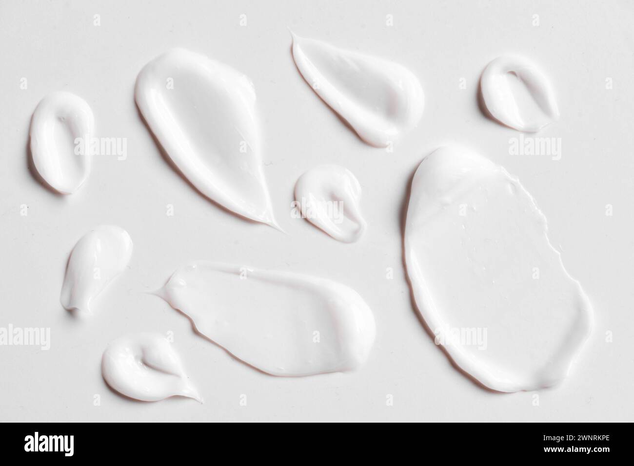 Motif de maculage de taches de crème cosmétique blanche sur fond blanc gros plan. Ensemble de coups de produit cosmétique en gel. Banque D'Images