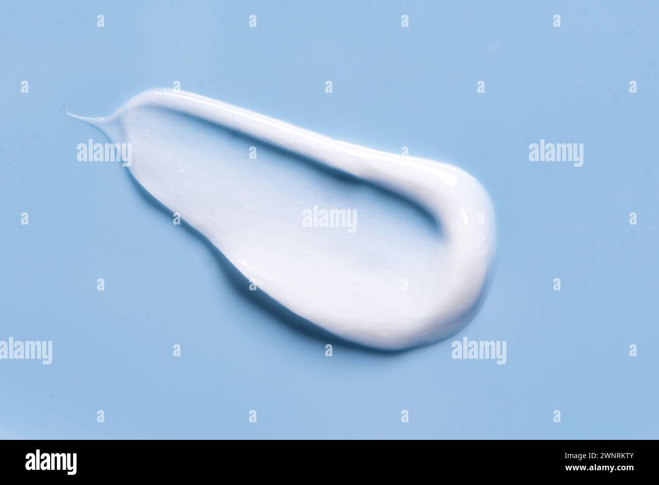 Maculage de smear de crème cosmétique blanche sur fond bleu. Produit cosmétique en gel léger. Banque D'Images