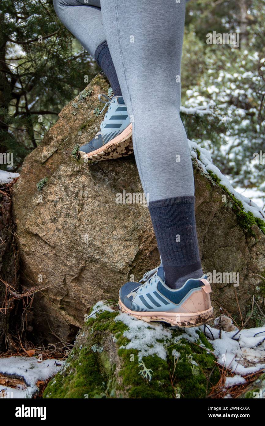 Femme marchant le long des sentiers de montagne enneigés avec des chaussures Adidas Terrex pour une utilisation de trekking Banque D'Images