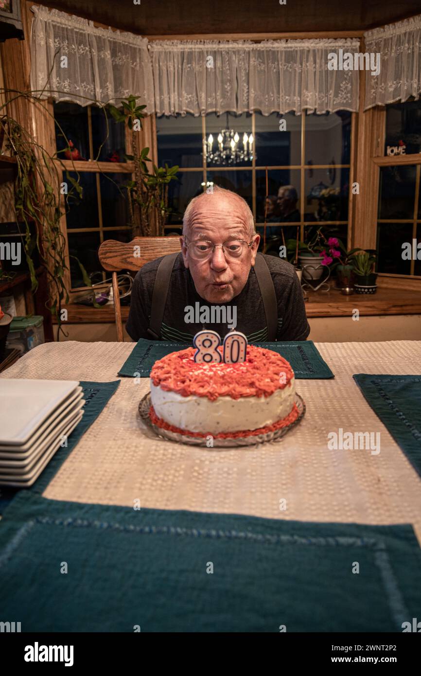 Vieil homme soufflant des bougies sur son gâteau d'anniversaire Banque D'Images