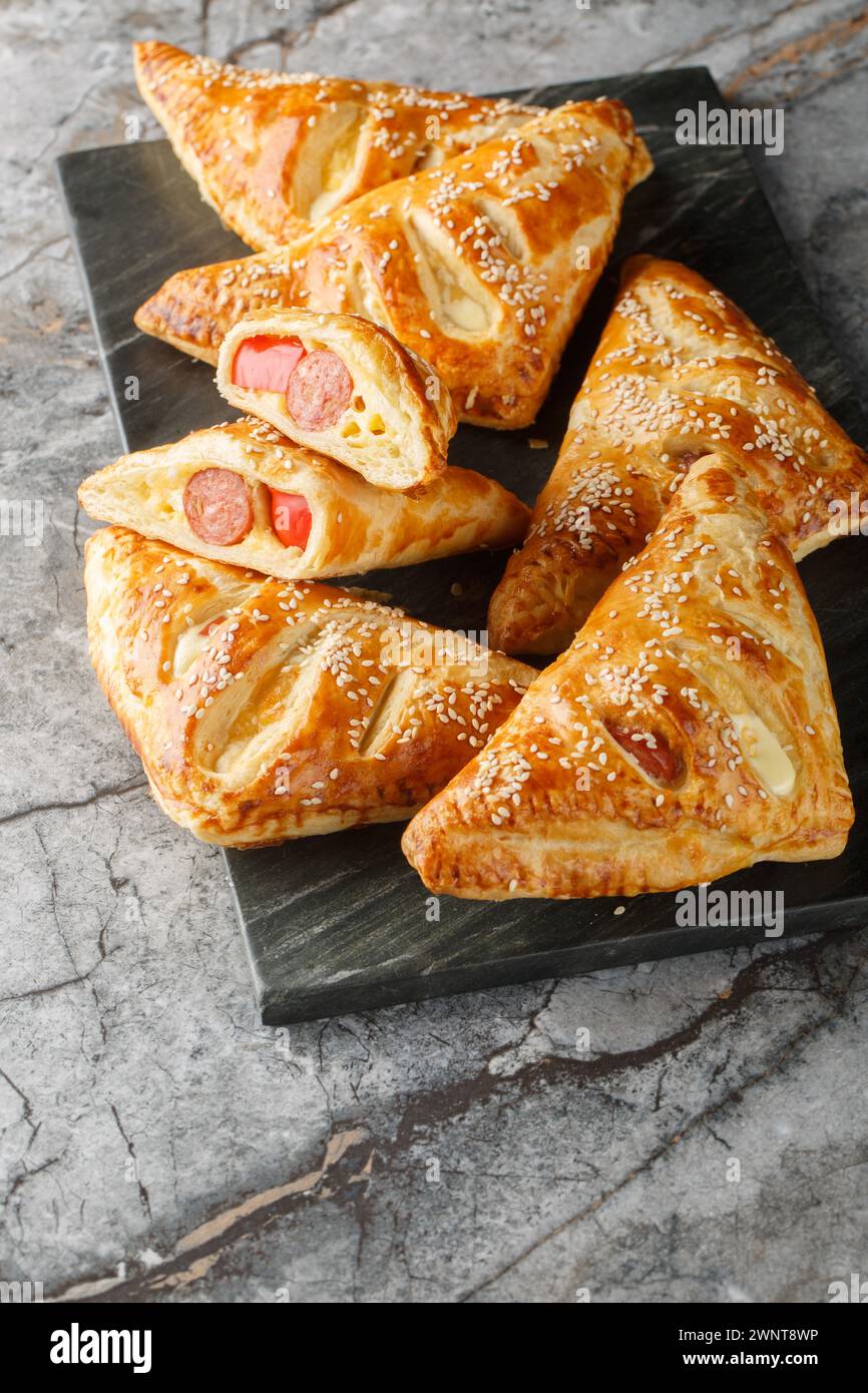 Saucisse et pâte feuilletée Turnovers en gros plan sur la planche de marbre sur la table. Vertical Banque D'Images
