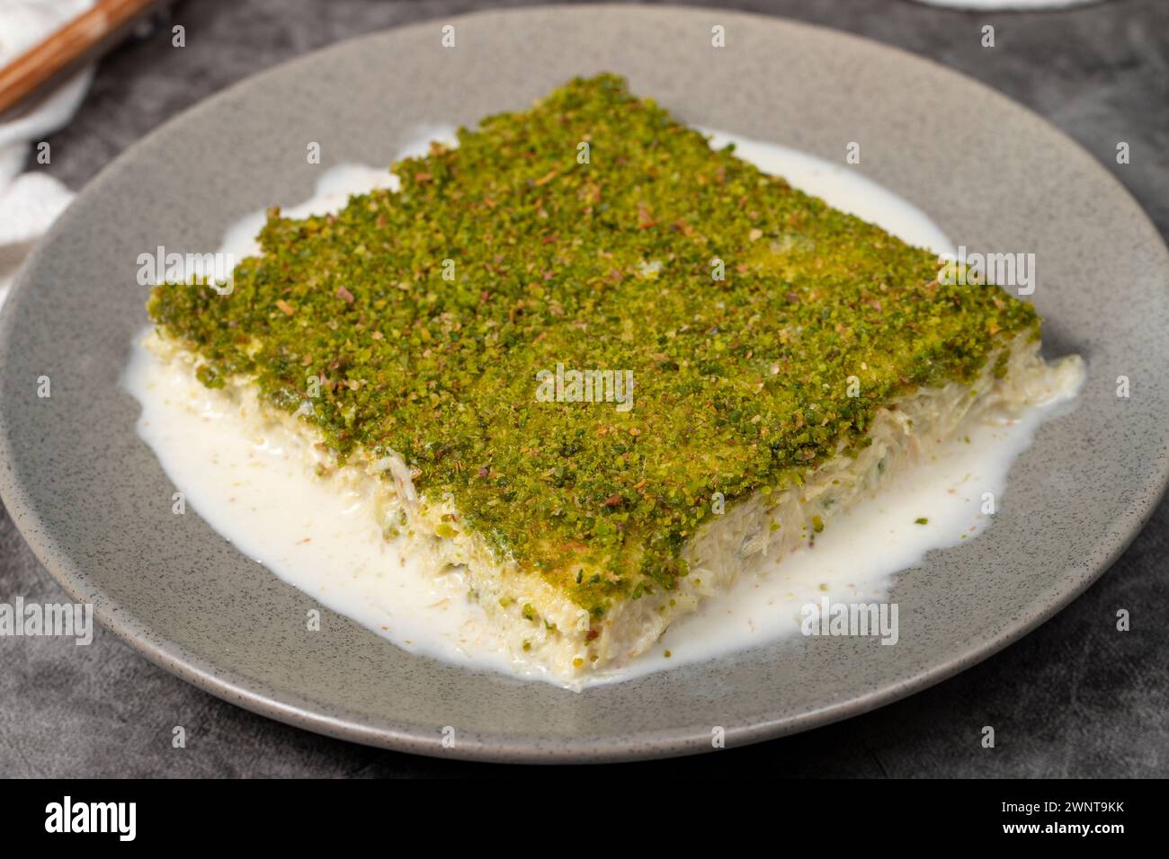 Kadayif froid avec pistache. Lait kadayıf dessert aux pistaches sur un fond sombre. Nom local soğuk kadayıf tatlısı. Gros plan Banque D'Images