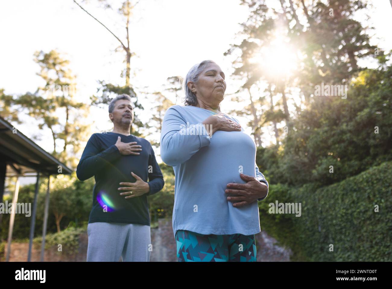 Femme biraciale senior et homme pratiquent le yoga à l'extérieur au lever du soleil à la maison Banque D'Images
