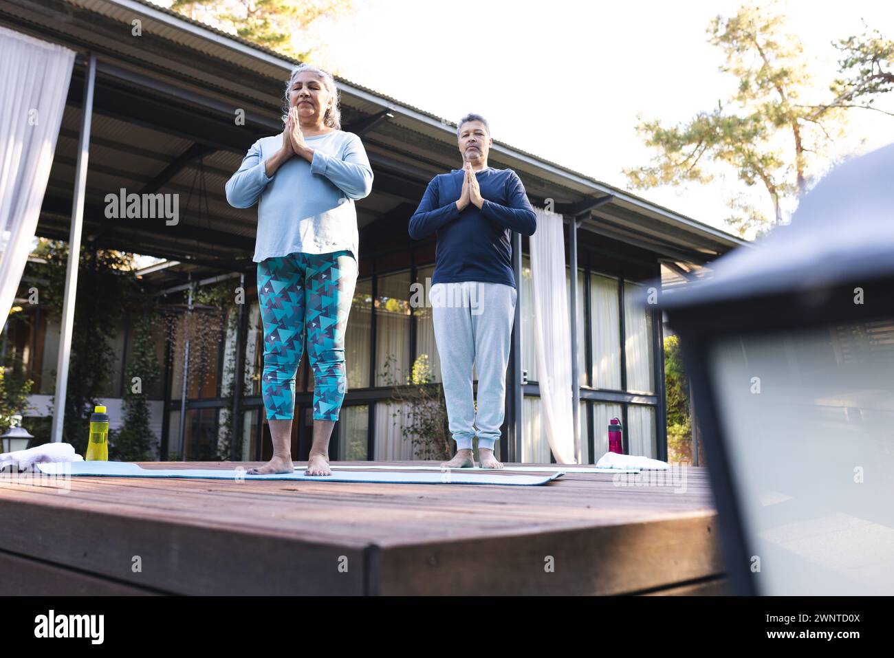 Femme biraciale senior et homme biracial pratiquent le yoga à l'extérieur, à la maison Banque D'Images