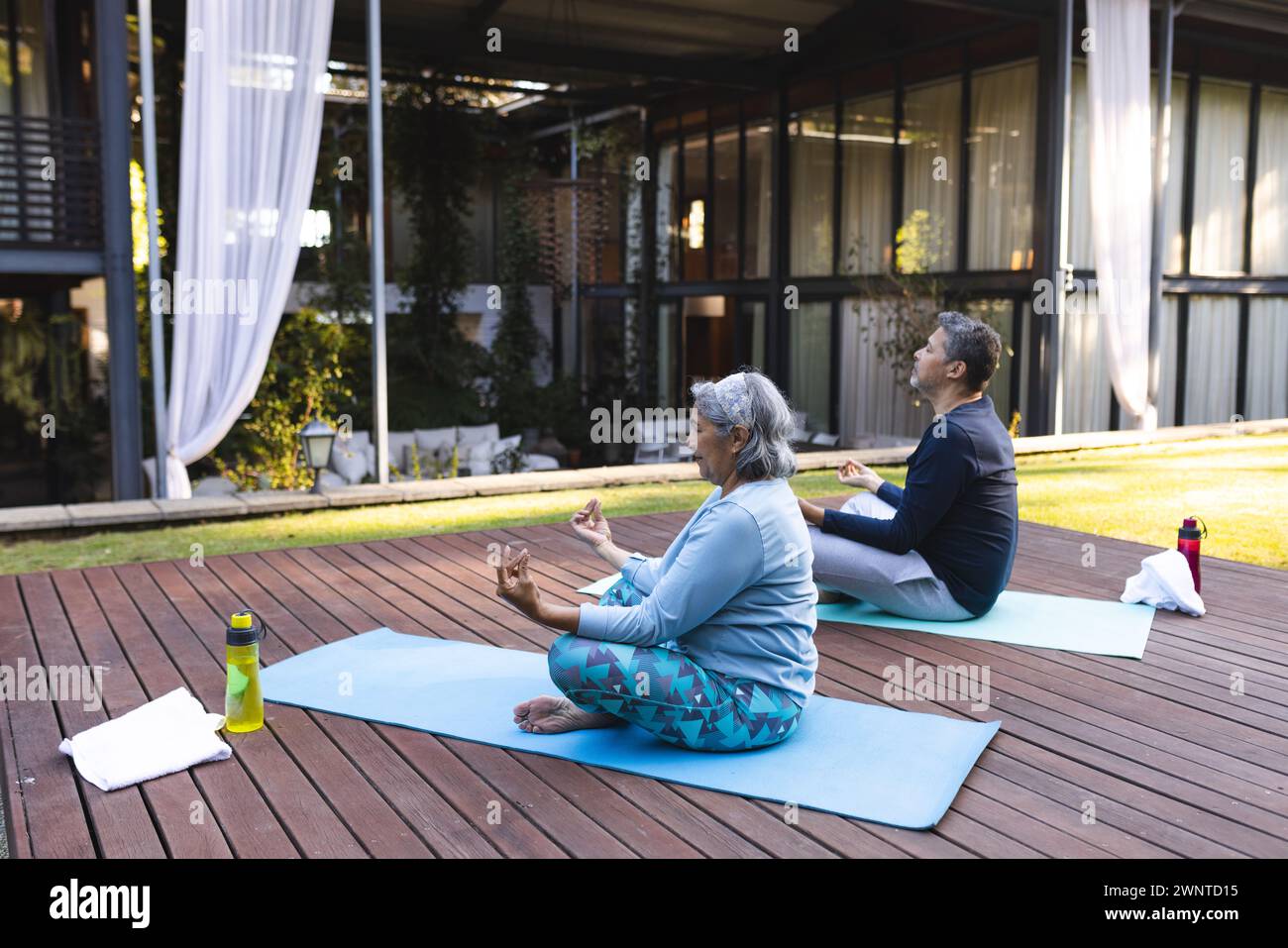 Couple biracial senior pratique le yoga à l'extérieur sur tapis à la maison Banque D'Images