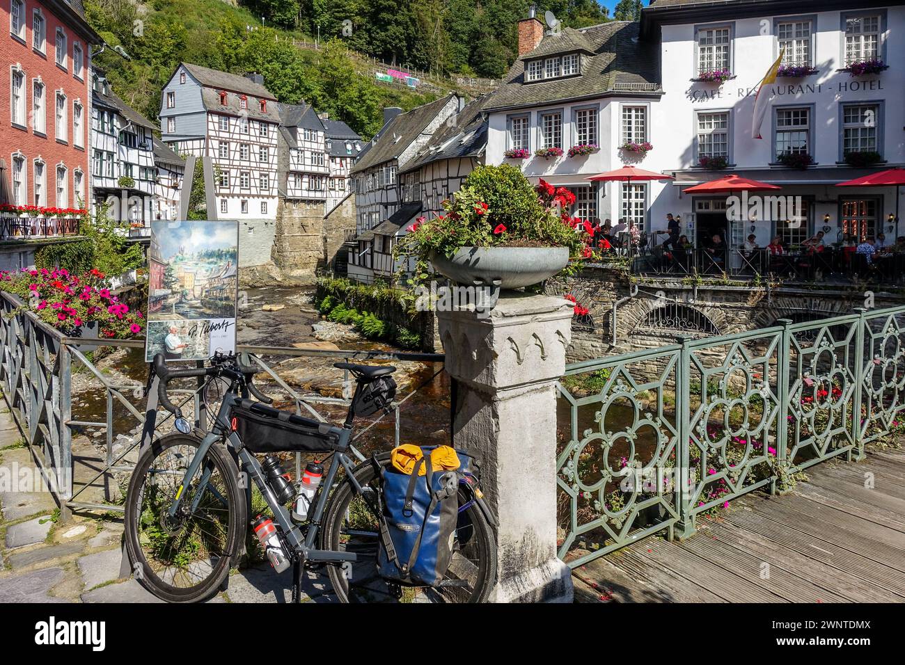 Vélo de gravier dans un village européen pittoresque (Monschau, Allemagne) avec des maisons à colombages et un pont fleuri sur un ruisseau Banque D'Images