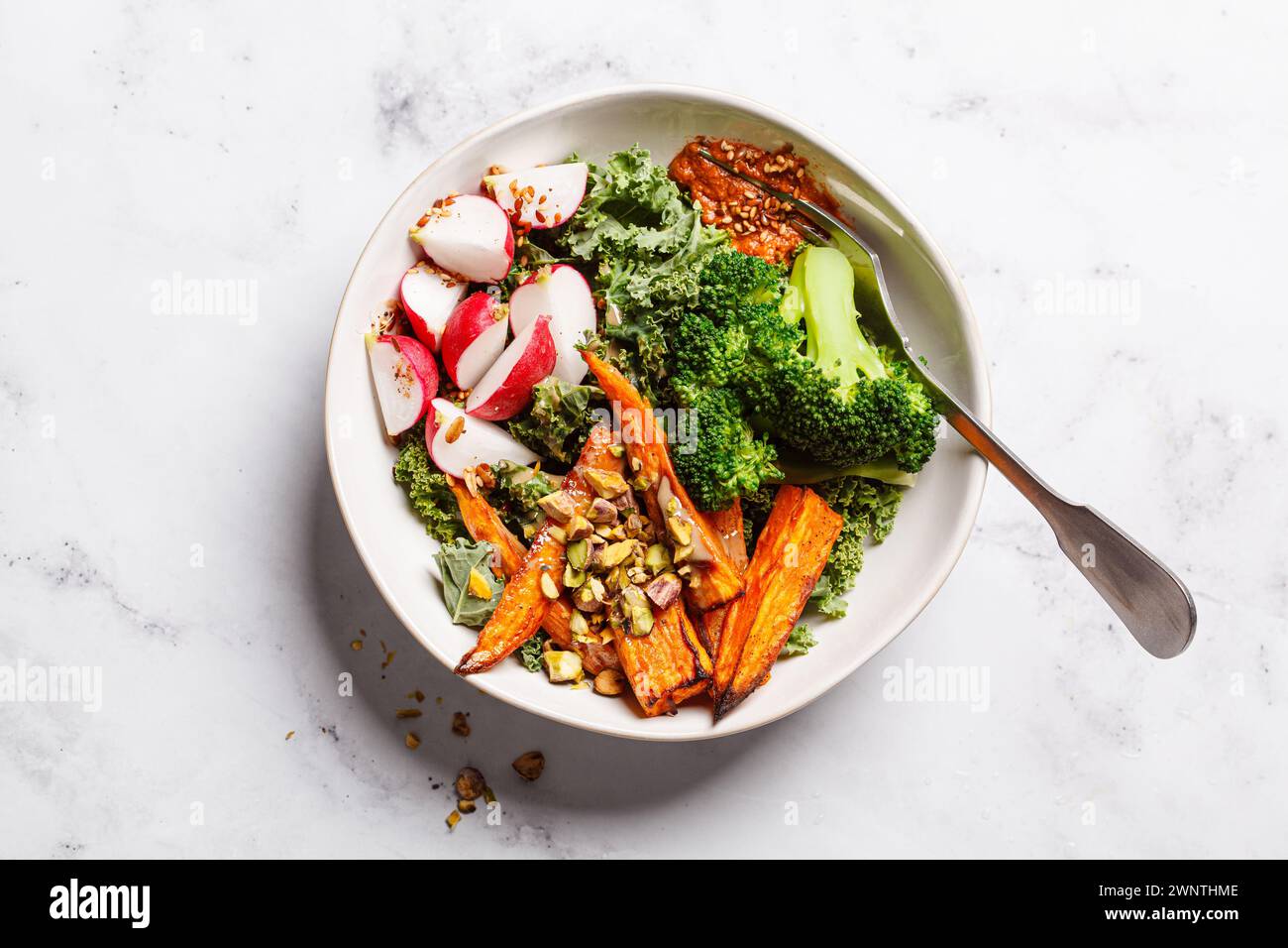 Bol végétalien avec chou frisé, brocoli, patate douce cuite au four, radis et pesto rouge, vue de dessus. Banque D'Images