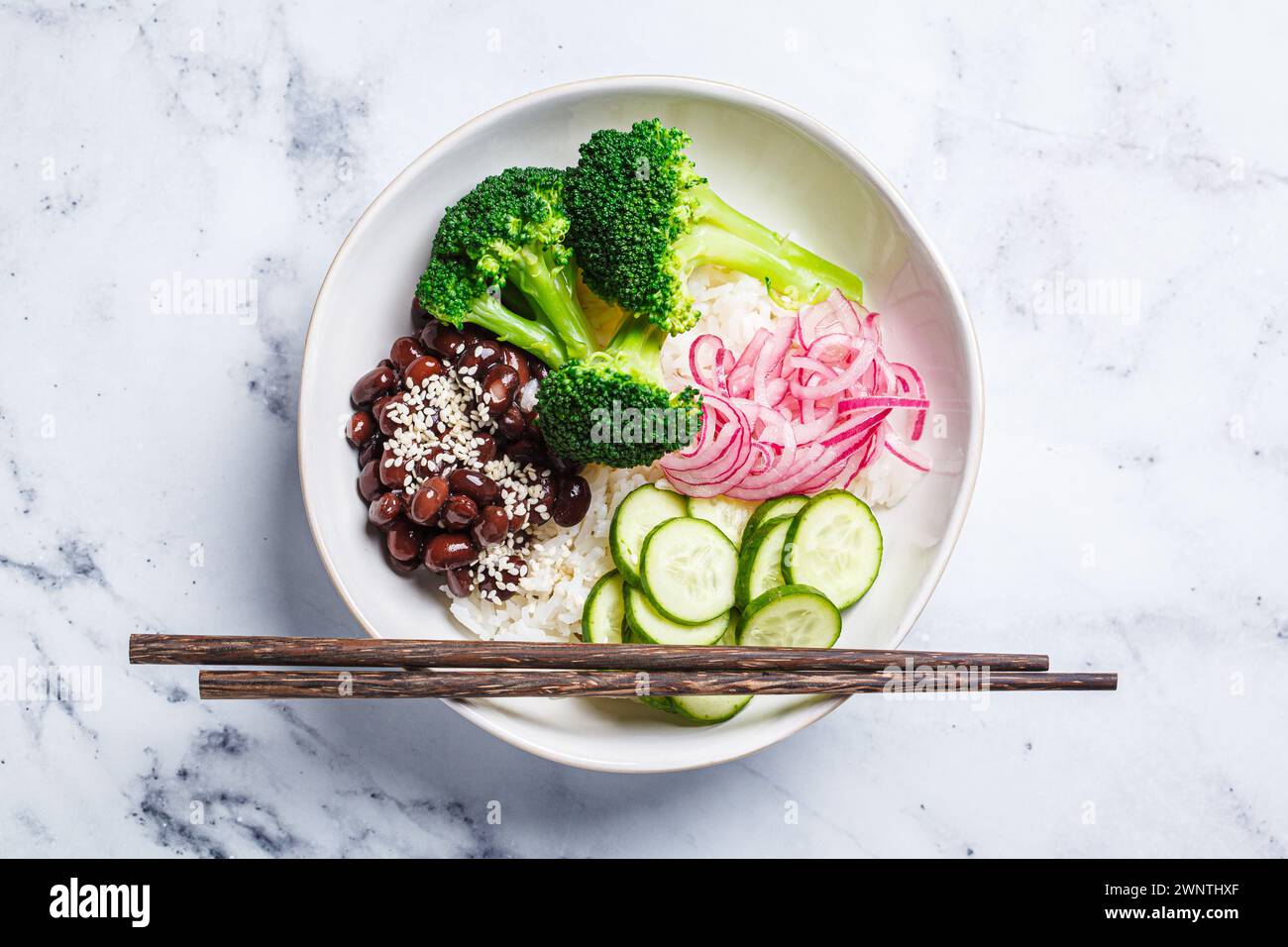 Vegan Poke. Bol avec riz, brocoli, concombre, haricots et oignon rouge mariné, fond de marbre blanc, vue de dessus. Banque D'Images