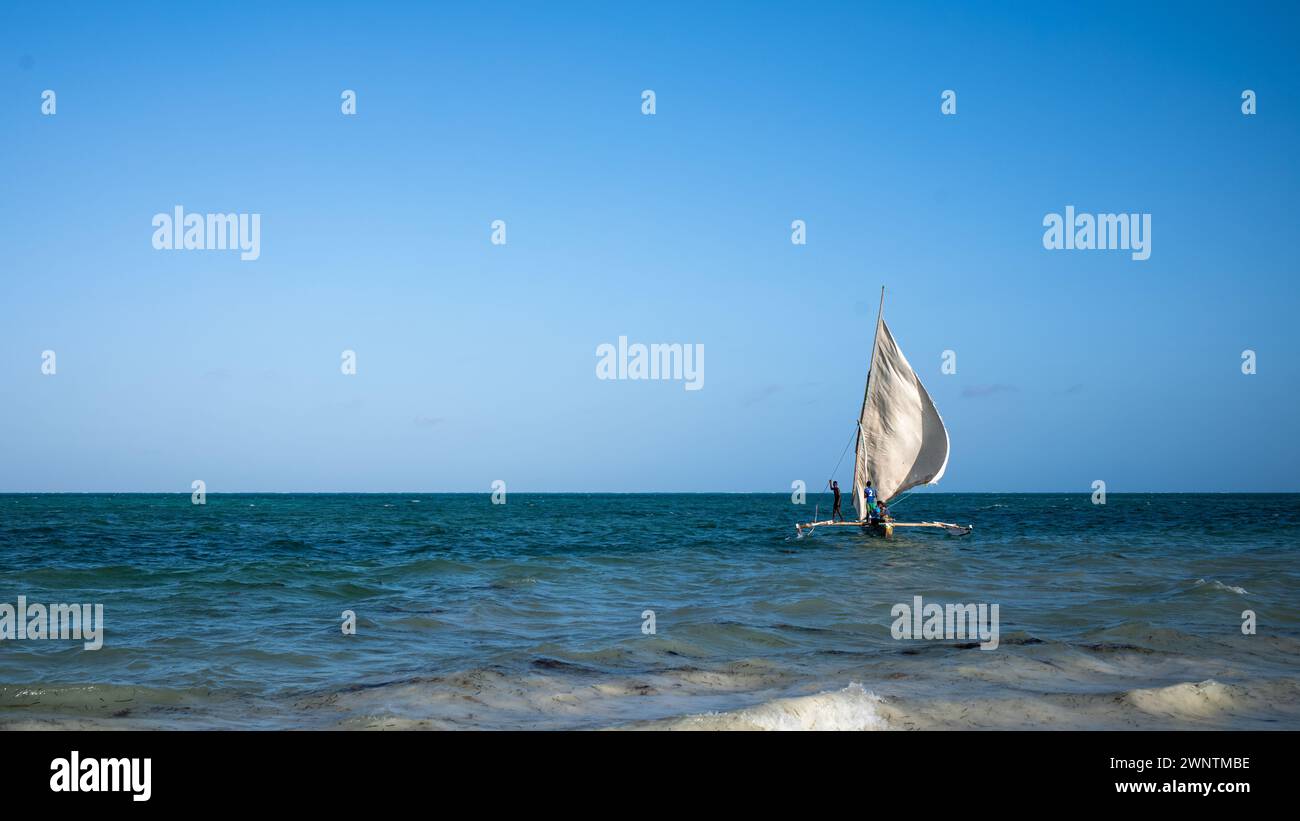 Les pêcheurs emmènent des touristes occidentaux pour un voyage dans leur boutre traditionnel à voile, Jambiani, Zanzibar, Tanzanie Banque D'Images