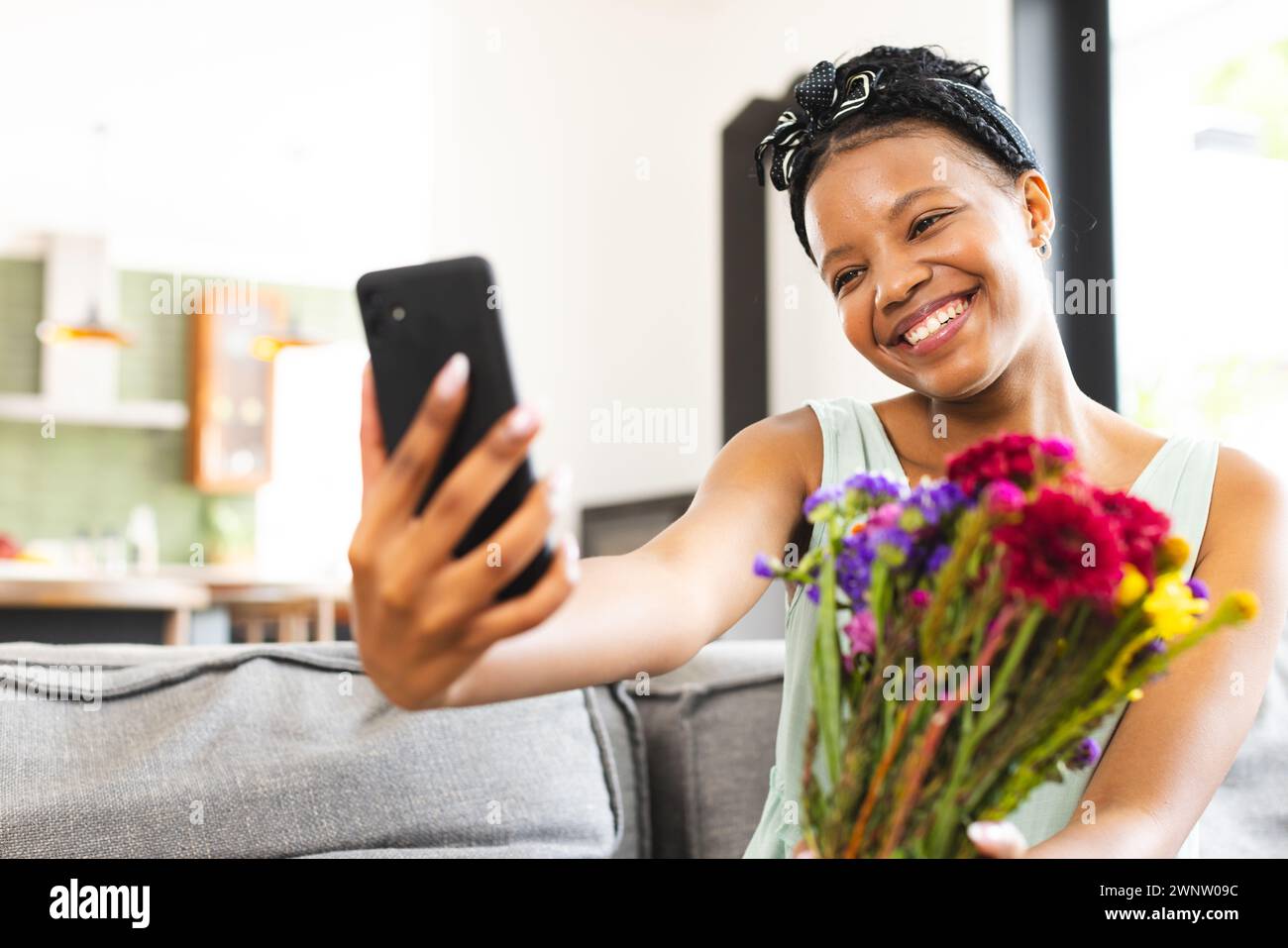 Jeune femme afro-américaine prend un selfie avec un bouquet de fleurs colorées avec espace copie Banque D'Images