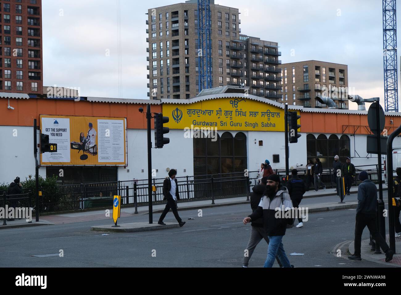 Les hommes traversent la route devant un grand Gurdwara sikh à Southall, une région de l'ouest de Londres avec une importante population ethniquement sikh Banque D'Images