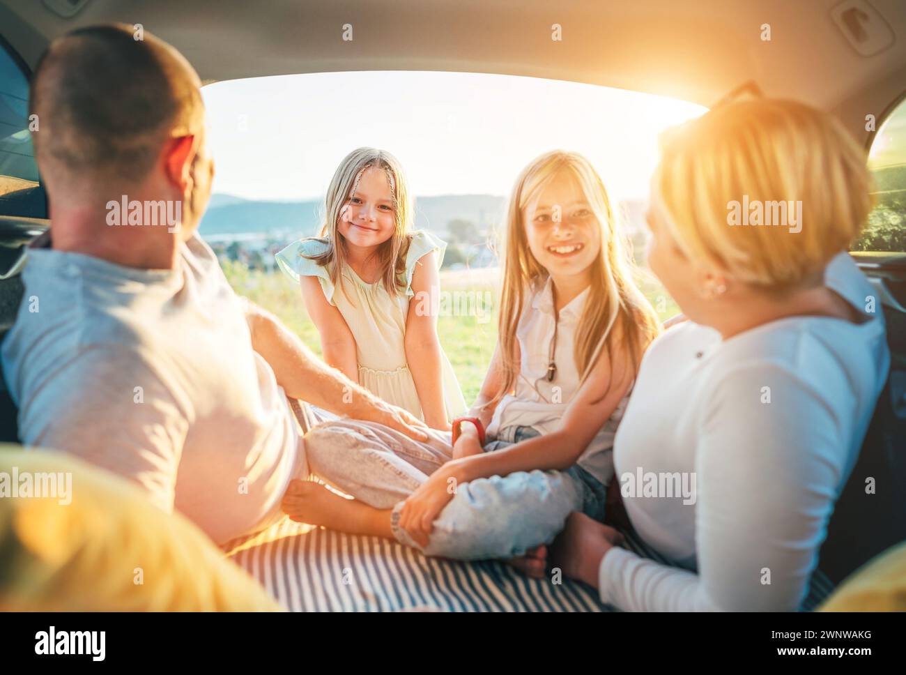 Portrait de petites sœurs souriantes heureuses. Heureux jeune couple avec deux filles à l'intérieur du coffre de la voiture pendant auto trop. Ils sourient, rient et Banque D'Images