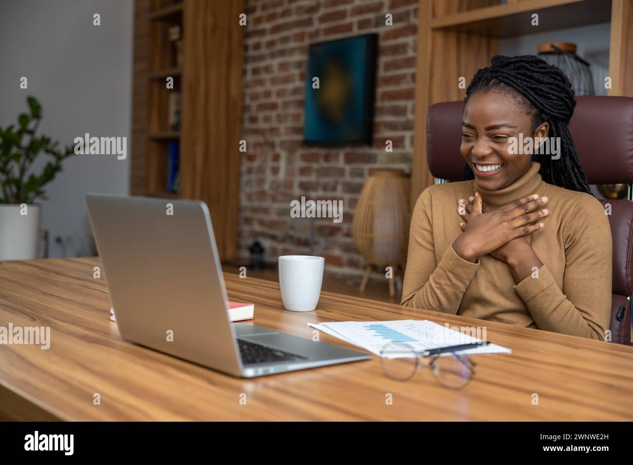 Femme joyeuse avec des dreadlocks à l'aide d'un ordinateur portable s'engage dans l'éducation virtuelle menant des webinaires Banque D'Images
