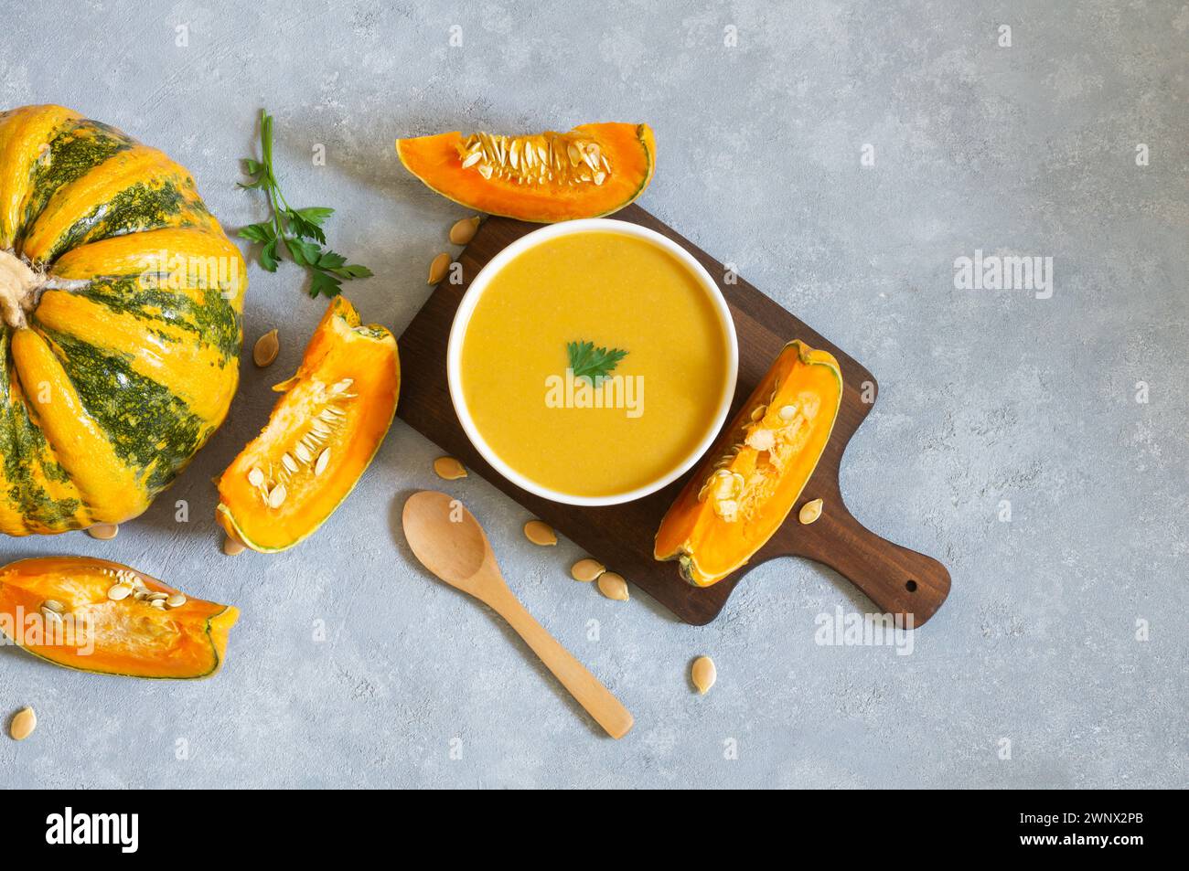 Soupe de carottes à la citrouille maison avec persil dans un bol et citrouilles fraîches sur fond rustique Banque D'Images
