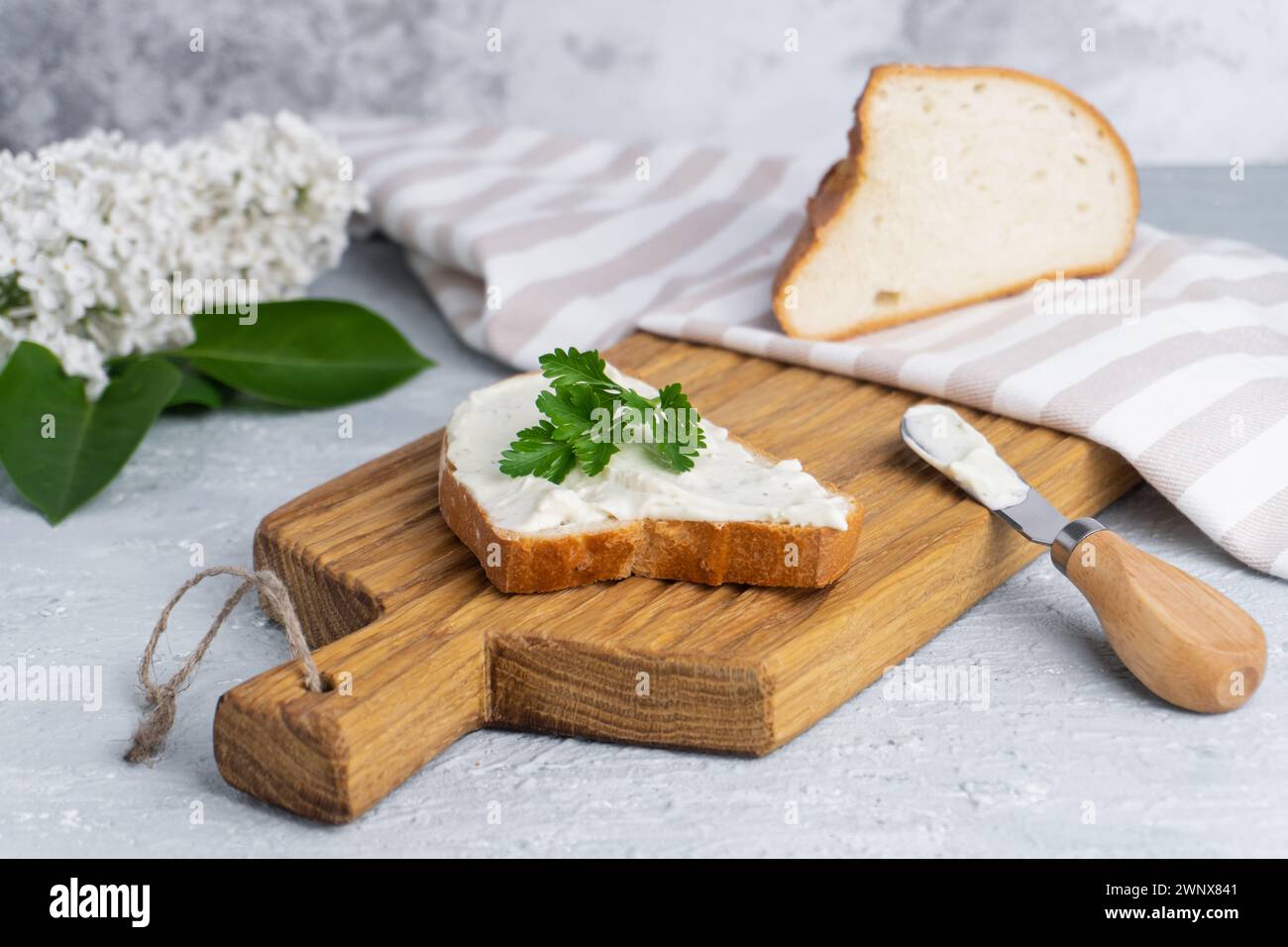Fromage à la crème aux herbes et assaisonnement sur une tranche de pain de seigle frais croquant avec un couteau à fromage à proximité Banque D'Images