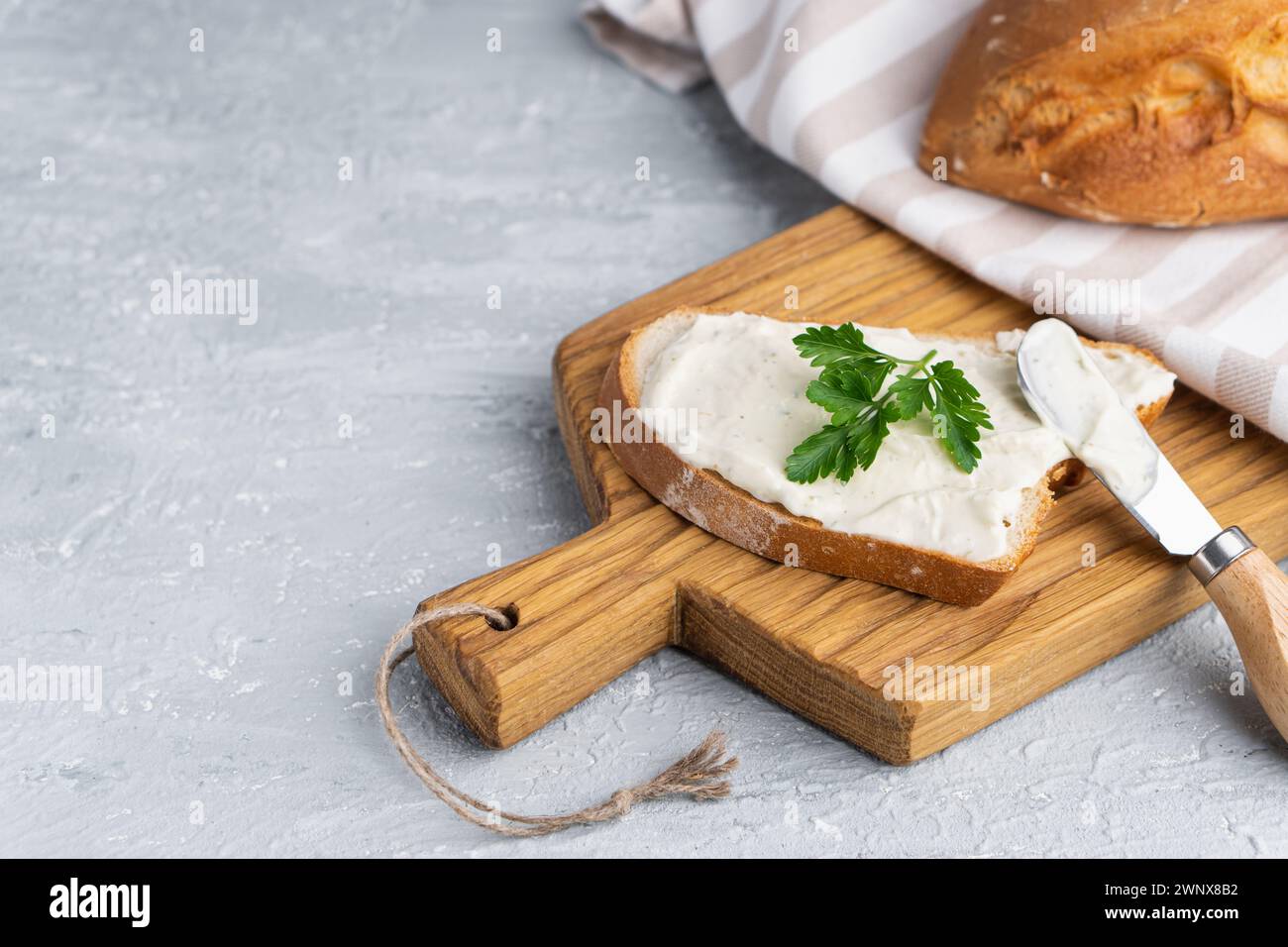 Fromage à la crème aux herbes et assaisonnement sur une tranche de pain de seigle frais croquant avec un couteau à fromage à proximité Banque D'Images