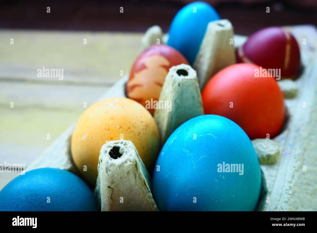 Oeufs multicolores peints à la gouache et à la pelure d'oignon dans une boîte en carton sur un fond de table en bois. Dix œufs durs. Affiche de carte postale pour Pâques Banque D'Images