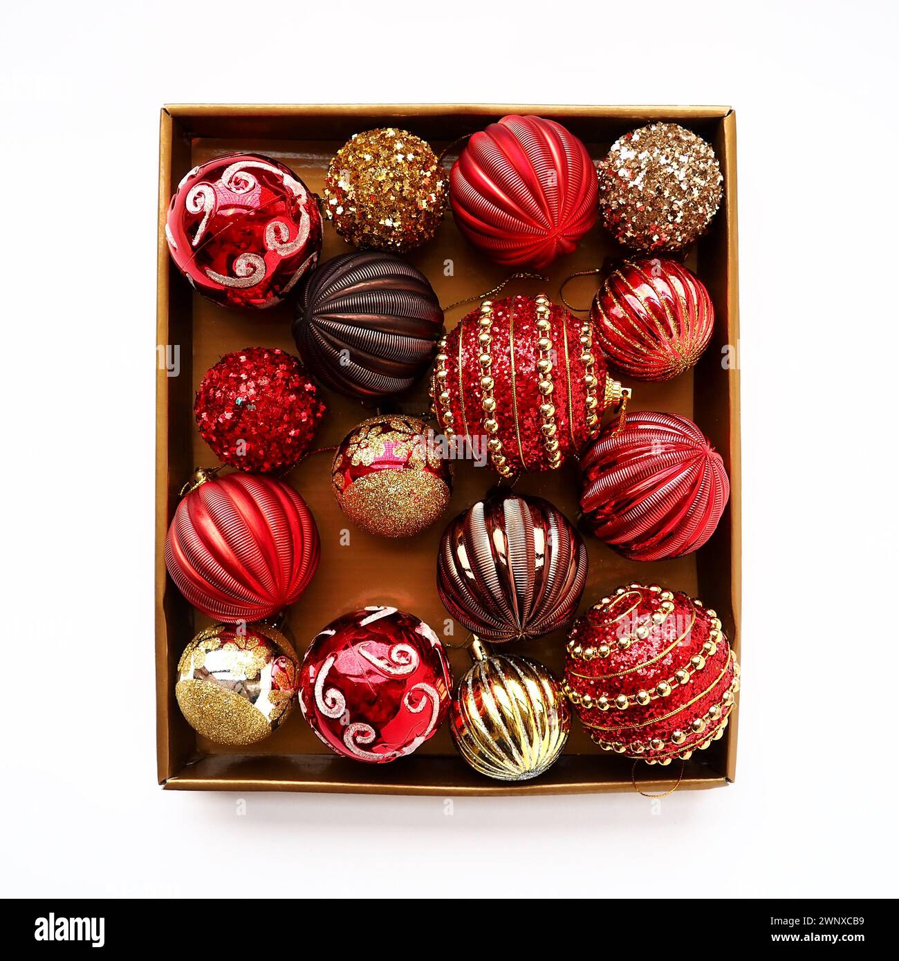 Décorations de Noël dans une boîte sur un fond blanc. Belles boules rouges et dorées avec des étincelles et des rayures. Préparation pour le nouvel an Noël Banque D'Images