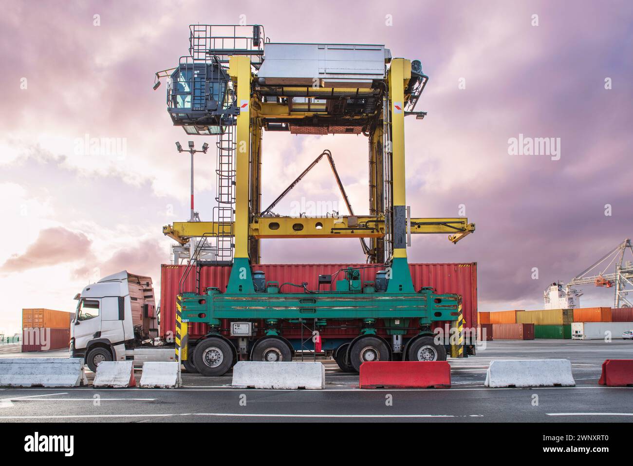 Déchargement de conteneurs dans un port commercial à l'aide de grues et de camions Banque D'Images