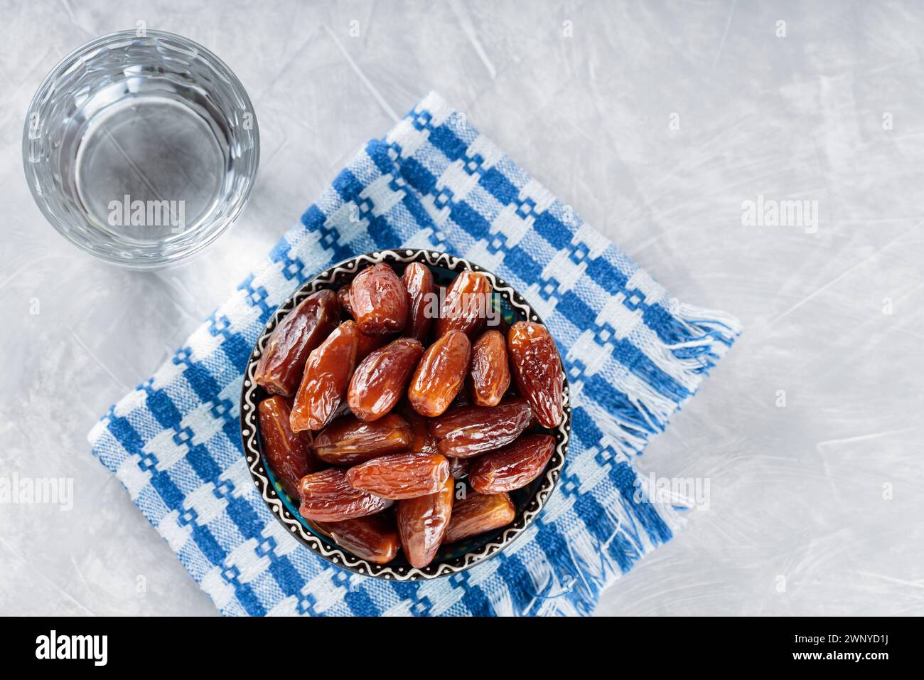 Dattes séchées dans un bol et un verre d'eau sur une serviette en lin, nourriture Ramadan, espace copie, vue de dessus Banque D'Images